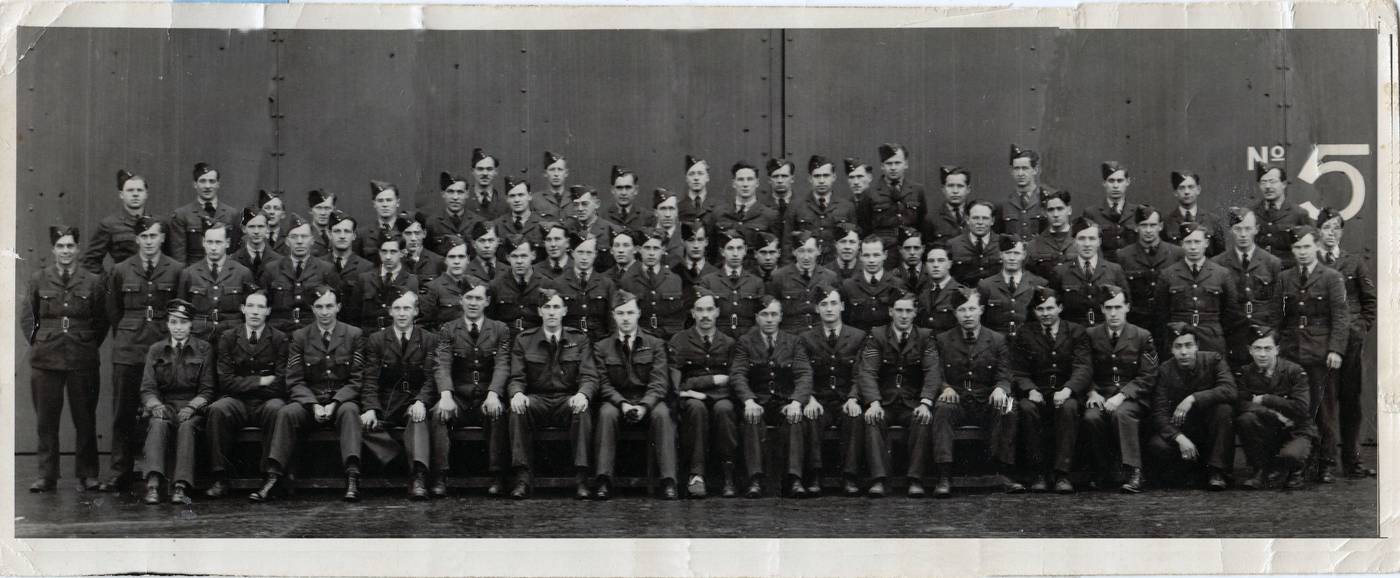 Group photograph of airmen in front of a hangar door marked No. 5